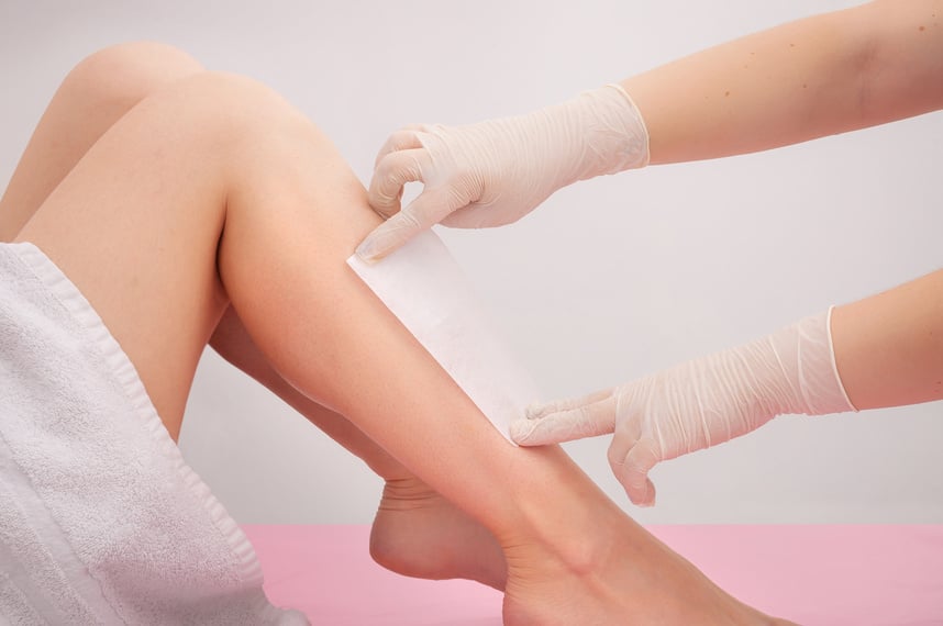 Spa professional doing waxing. Woman waxing her legs.