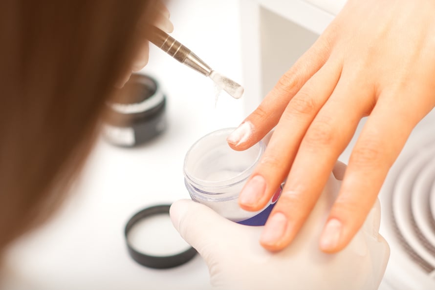 Manicure Master Applying Acrylic Powder on the Female Nails in a Beauty Salon. Strengthening of Nails Acrylic Powder.